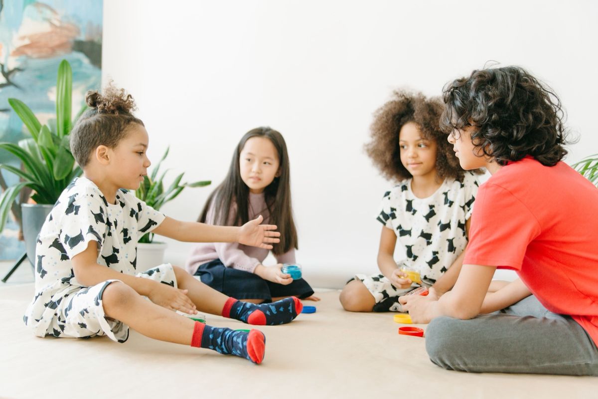 Children sitting in a circle, talking and playing a game
