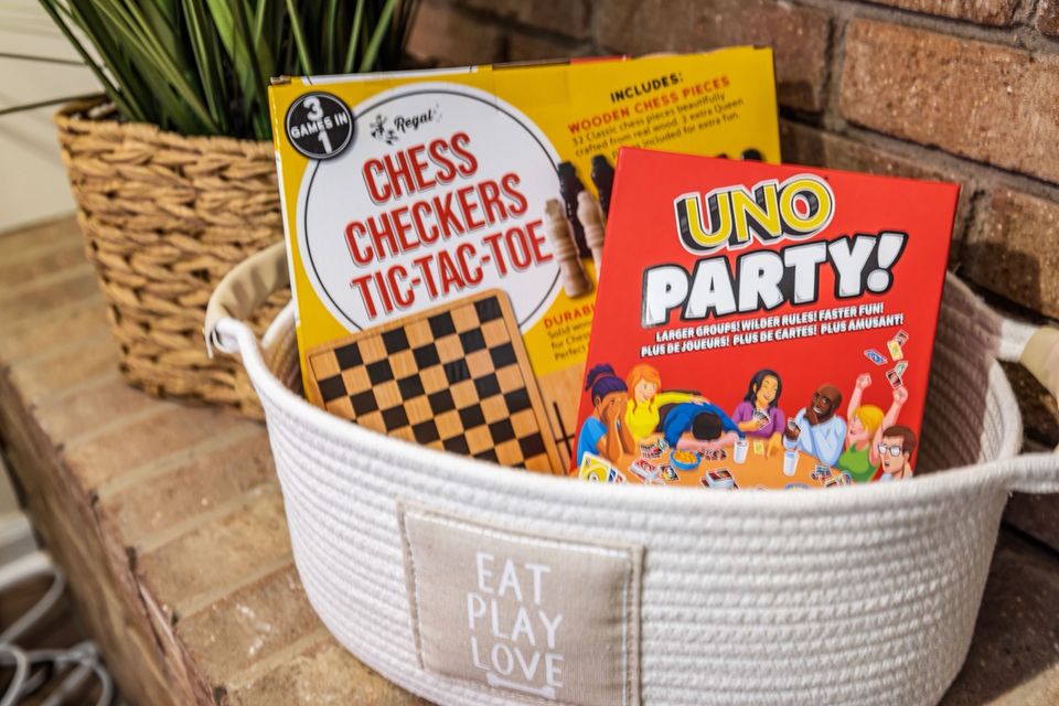 A white basket of board games including chess, checkers and UNO Party