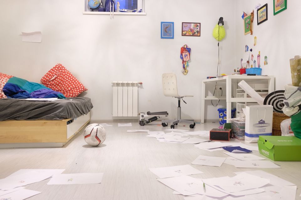 A messy child's bedroom with papers scattered on the floor