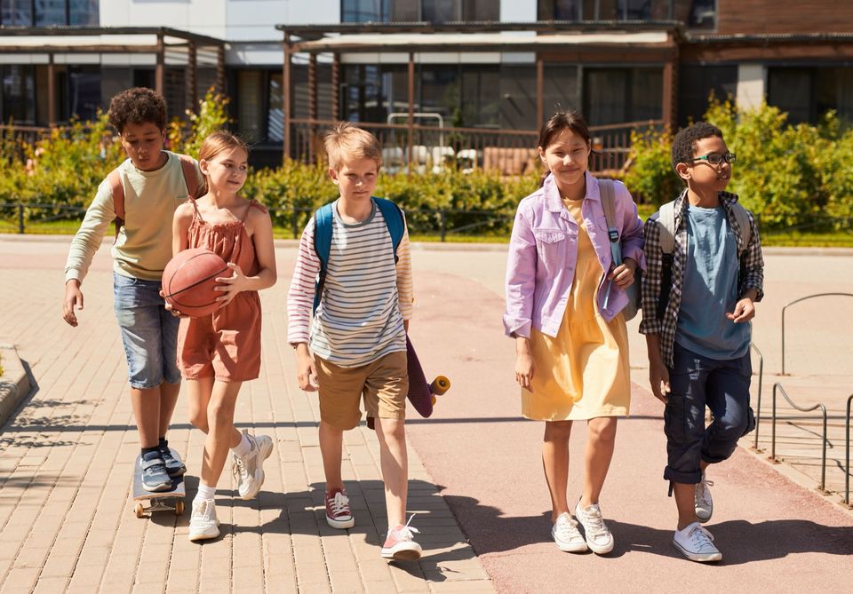 A group of teens with backpacks walking together outside a school building